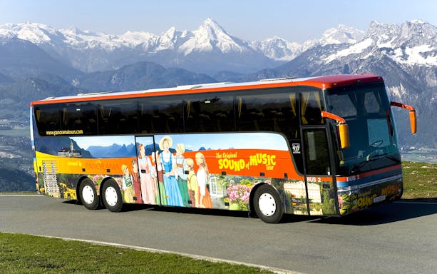 Original Sound of Music tour bus with mountain backdrop in Salzburg, Austria.