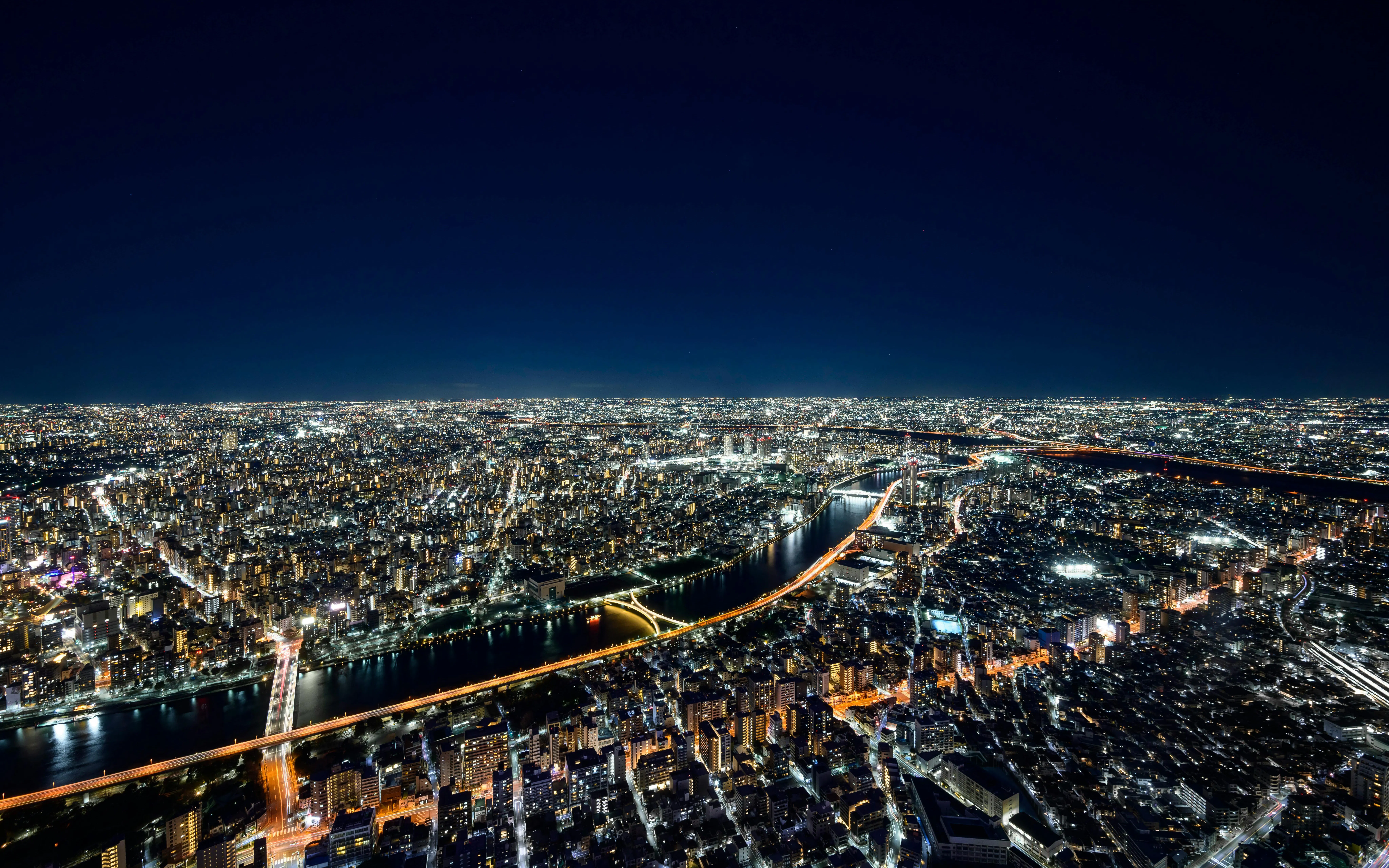 Tokyo cityscape view from Skytree Tembo Deck at night, showcasing illuminated buildings and river.