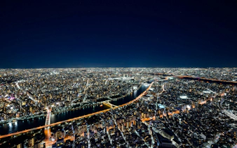 Tokyo cityscape view from Skytree Tembo Deck at night, showcasing illuminated buildings and river.