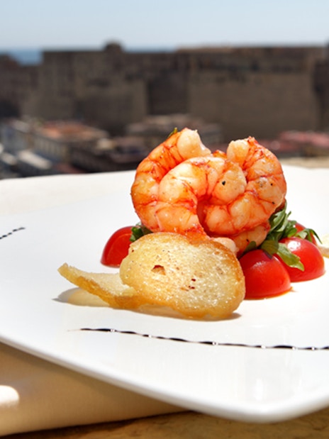 Shrimp dish on rooftop terrace overlooking Castel dell'Ovo in Naples.