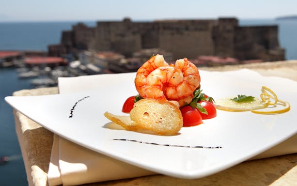 Shrimp dish on rooftop terrace overlooking Castel dell'Ovo in Naples.
