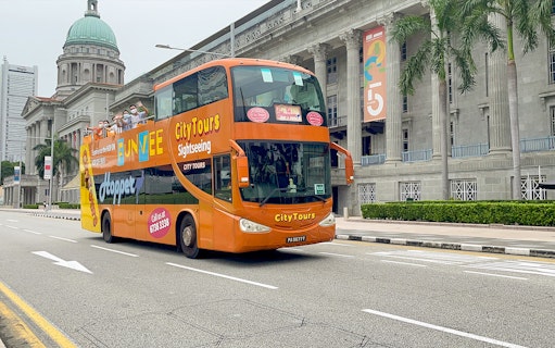 Open-top FunVee bus touring past historic building in Singapore.