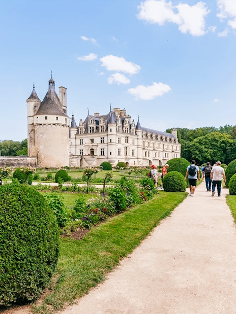 Visitors walking through gardens towards Chateau de Chenonceau, France.