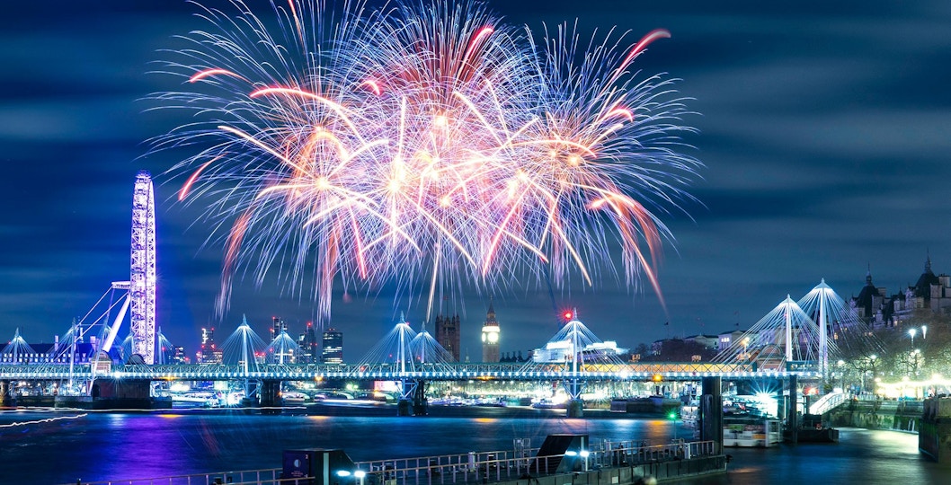 Fireworks over River Thames with London Eye and Big Ben on New Year's Eve.