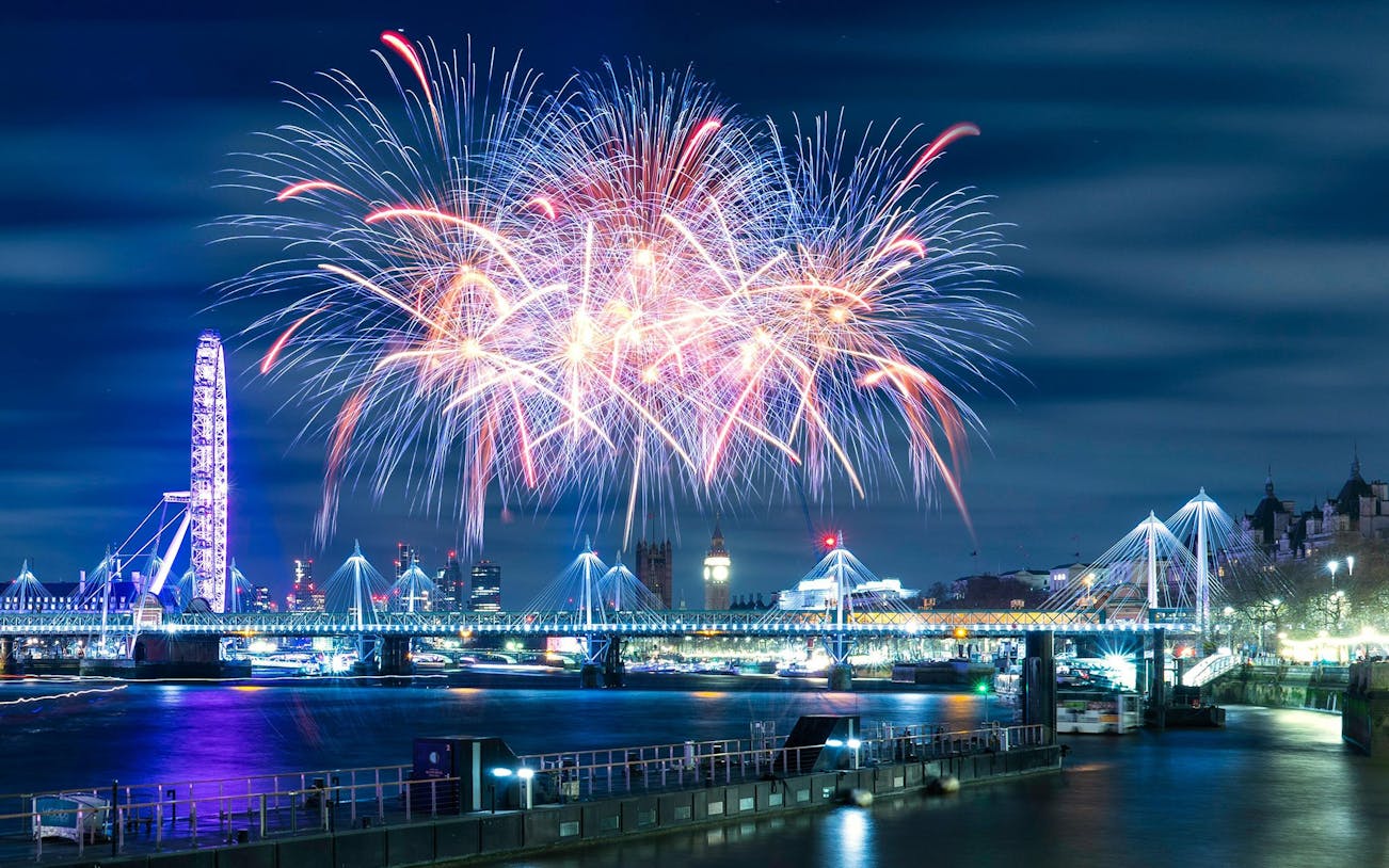 Fireworks over River Thames with London Eye and Big Ben on New Year's Eve.