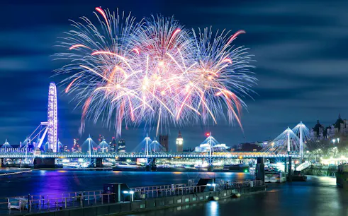 Fireworks over River Thames with London Eye and Big Ben on New Year's Eve.