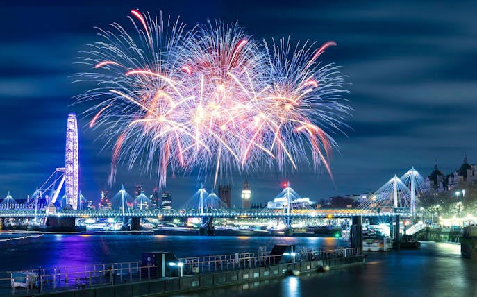 Fireworks over River Thames with London Eye and Big Ben on New Year's Eve.