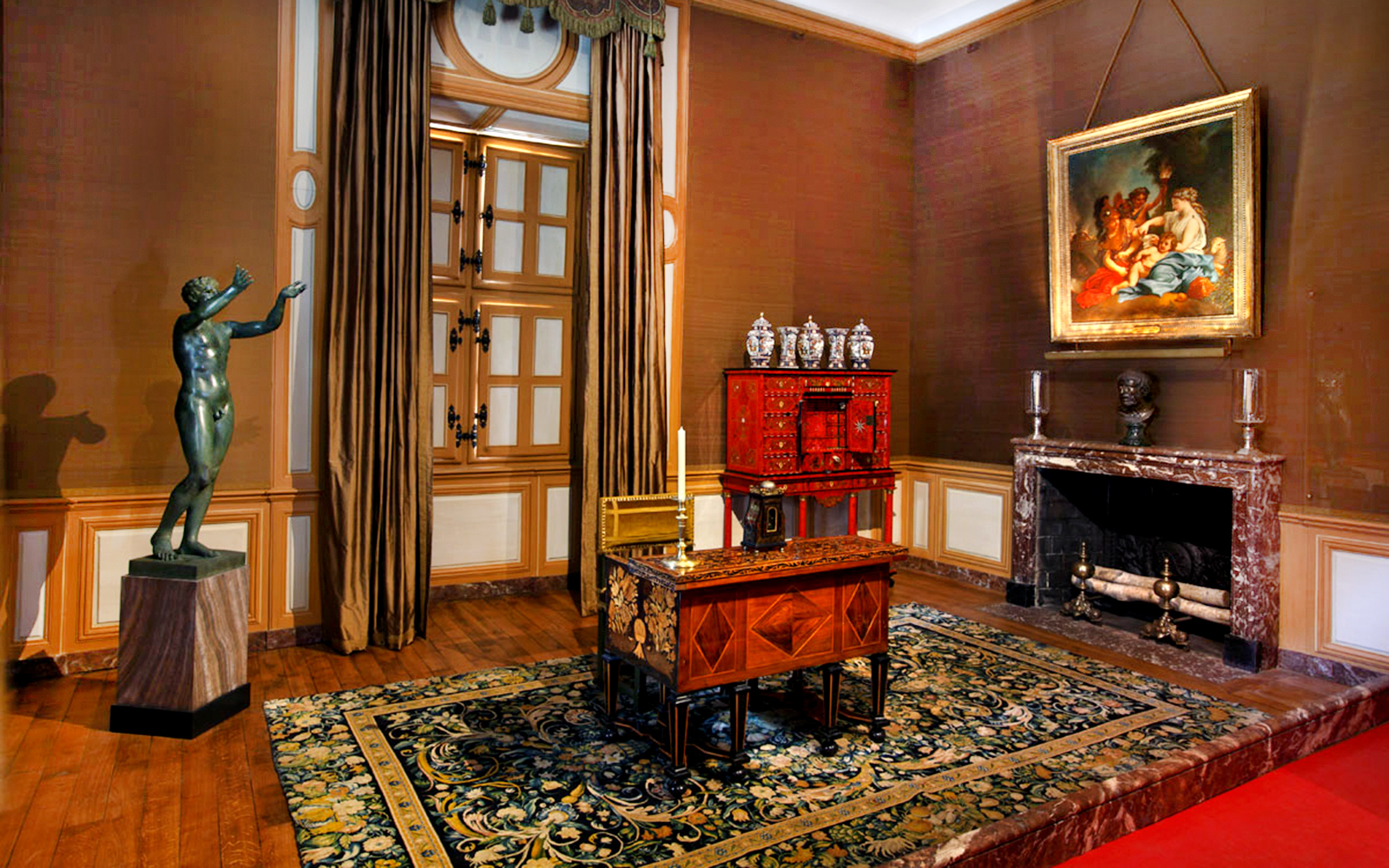Interior of Vaux-le-Vicomte Castle with ornate desk, statue, and painting.
