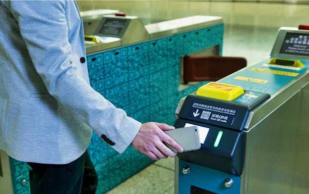 Person scanning phone at airport express turnstile for Sky100 combo ticket.
