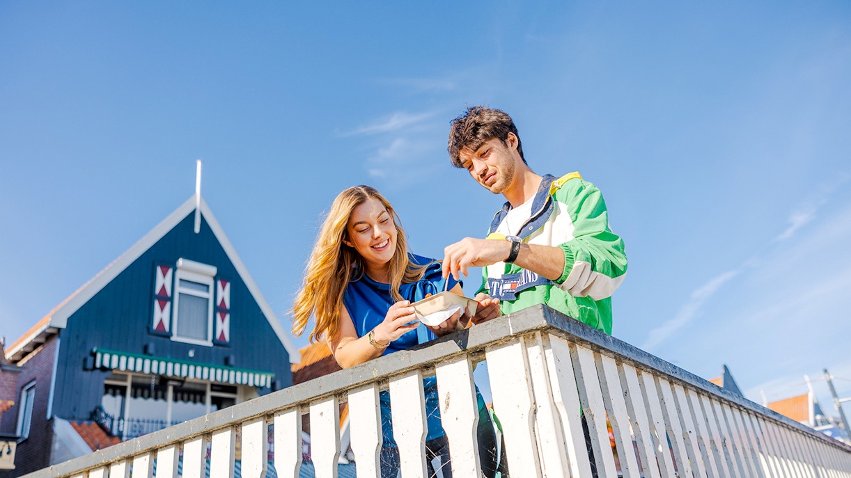 Guests enjoying snacks on a bridge in Volendam during the Zaanse Schans Tour.