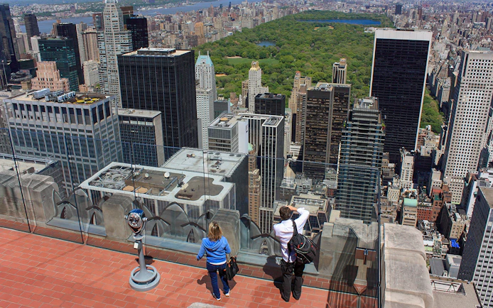 Visitors enjoying the view from Top of the Rock Observation Deck, overlooking New York City skyline and Central Park.
