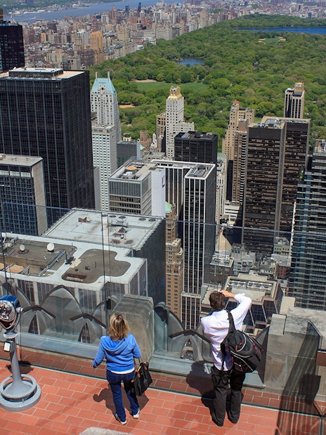 Visitors enjoying the view from Top of the Rock Observation Deck, overlooking New York City skyline and Central Park.