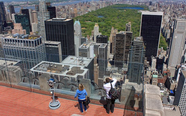 Visitors enjoying the view from Top of the Rock Observation Deck, overlooking New York City skyline and Central Park.