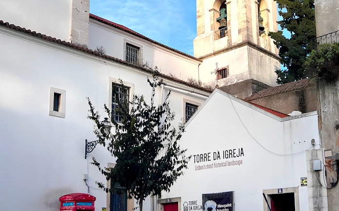Tower of St. George's Castle Church in Lisbon with bell tower and white facade.