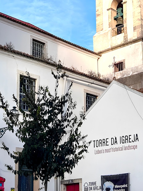 Tower of St. George's Castle Church in Lisbon with bell tower and white facade.