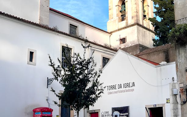 Tower of St. George's Castle Church in Lisbon with bell tower and white facade.