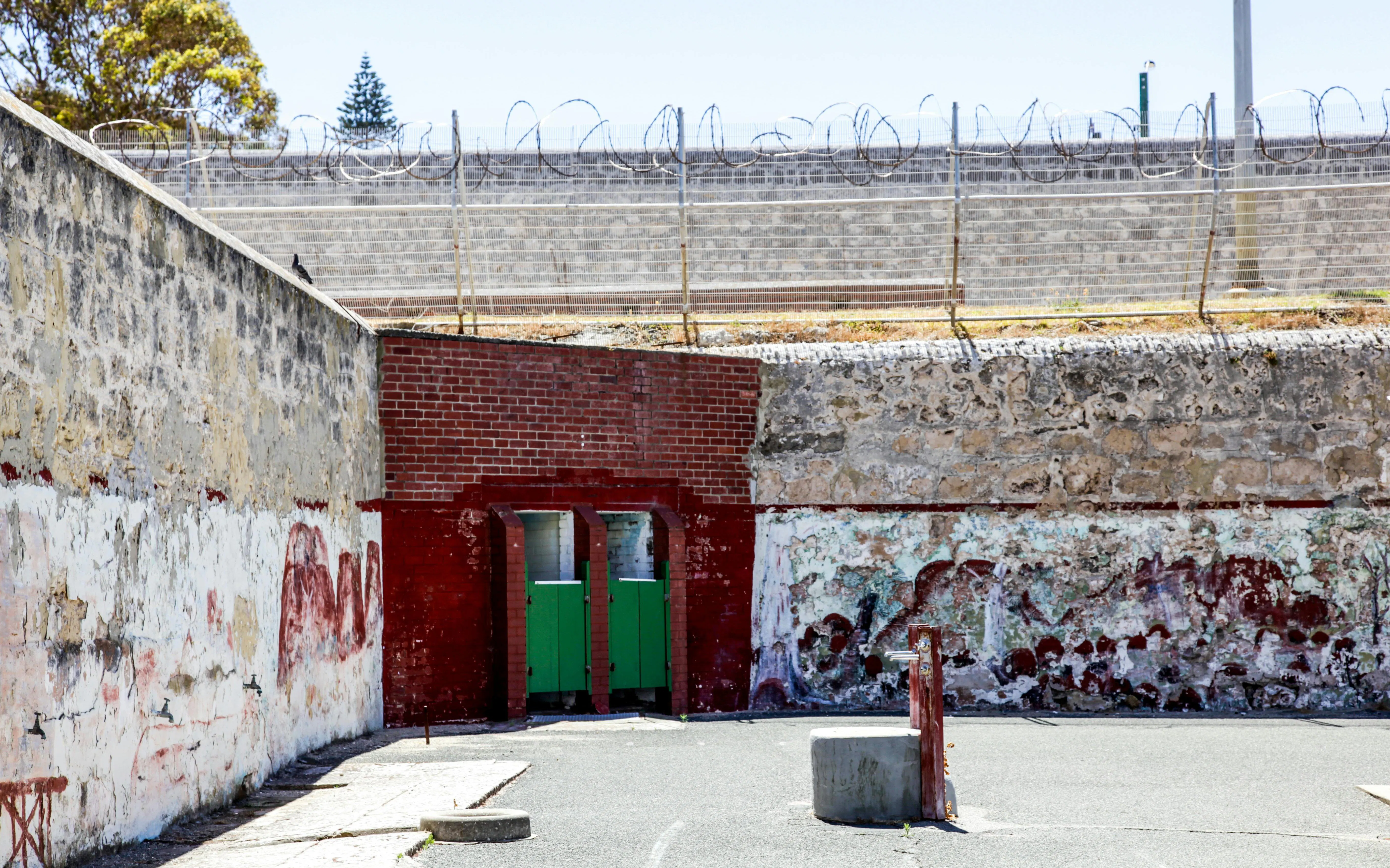 Fremantle Prison courtyard with weathered walls and barbed wire fence.