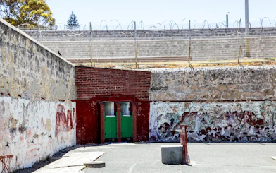 Fremantle Prison courtyard with weathered walls and barbed wire fence.