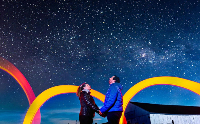 Couple stargazing under Milky Way in Calafate with colorful arches.