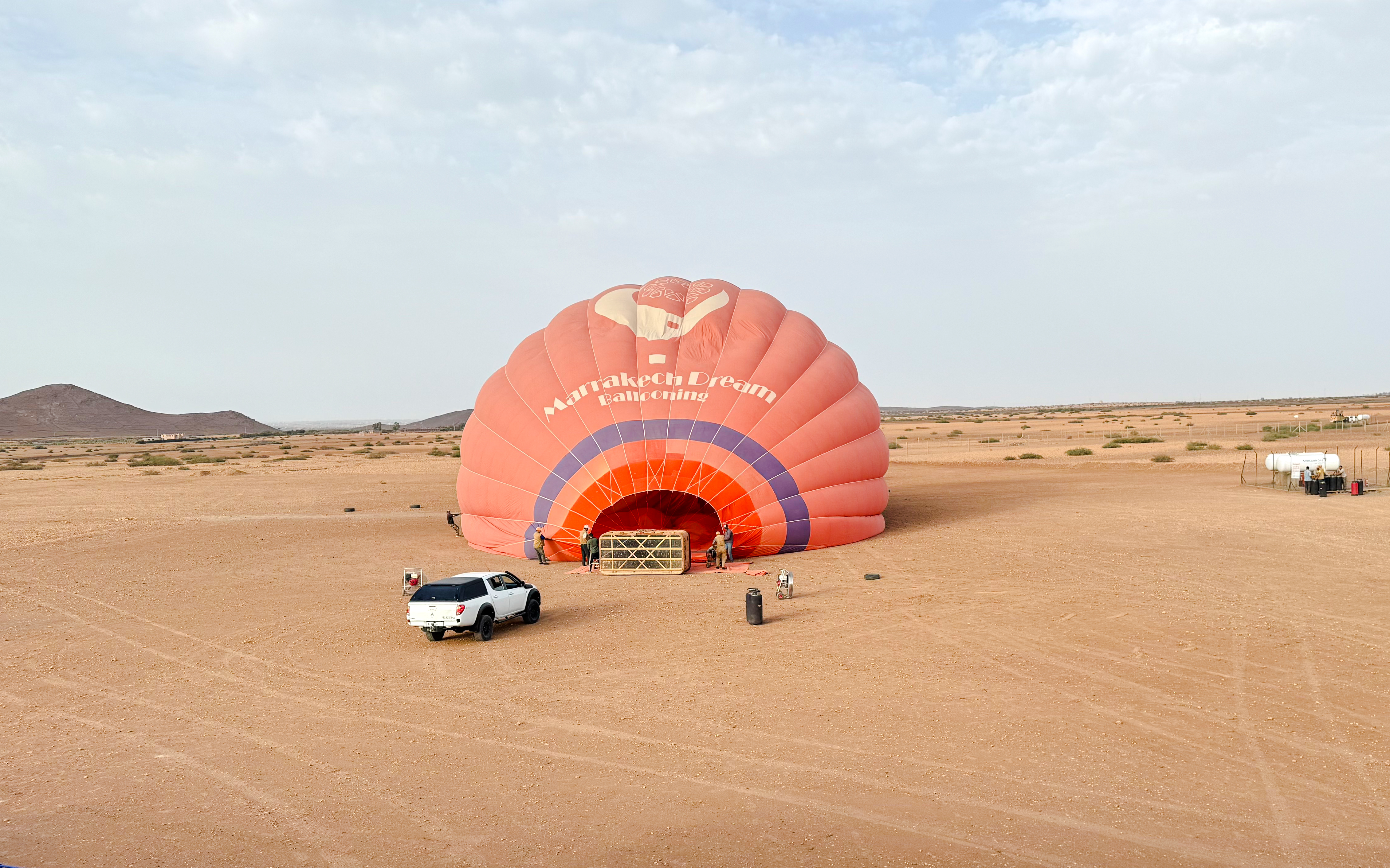 Crew inflating hot air balloon in Marrakech desert.