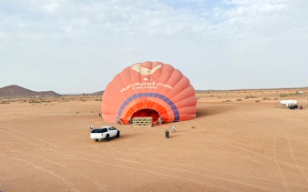 Crew inflating hot air balloon in Marrakech desert.