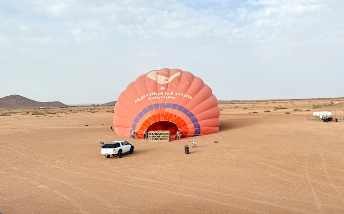 Crew inflating hot air balloon in Marrakech desert.