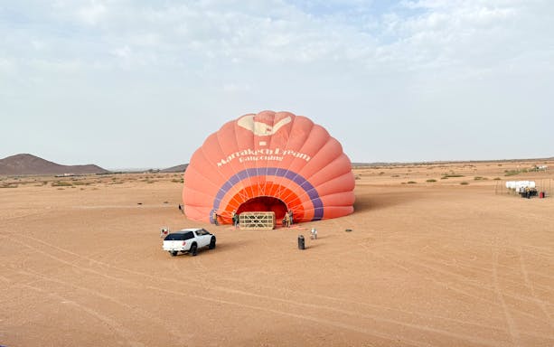 Crew inflating hot air balloon in Marrakech desert.
