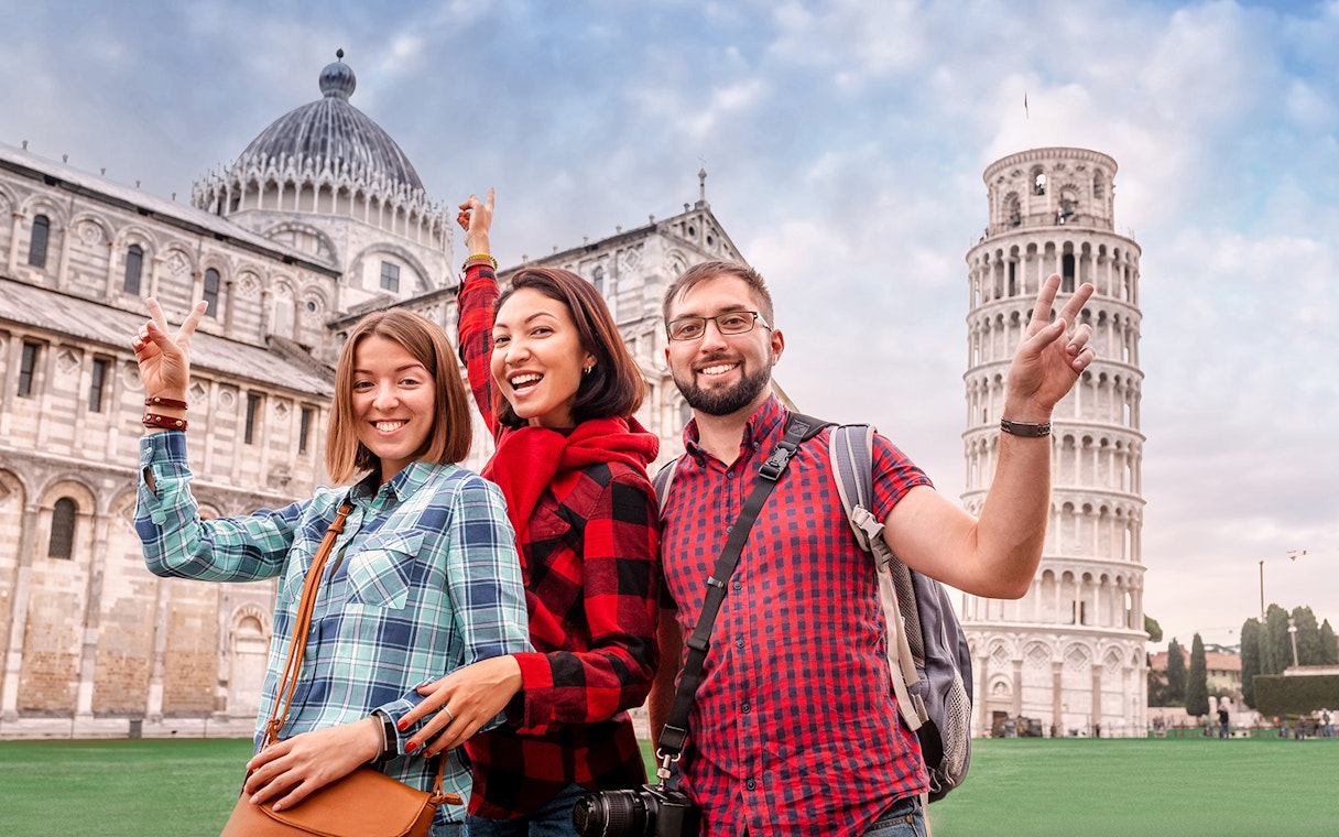 Tourists posing in front of the Leaning Tower of Pisa during a guided tour from Florence.