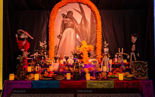 Frida Kahlo altar with marigold arch, skeleton figures, and traditional offerings.