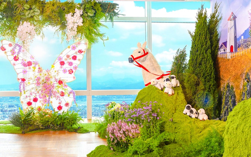 Colorful butterfly display and animal figures with Taipei 101 view in background.