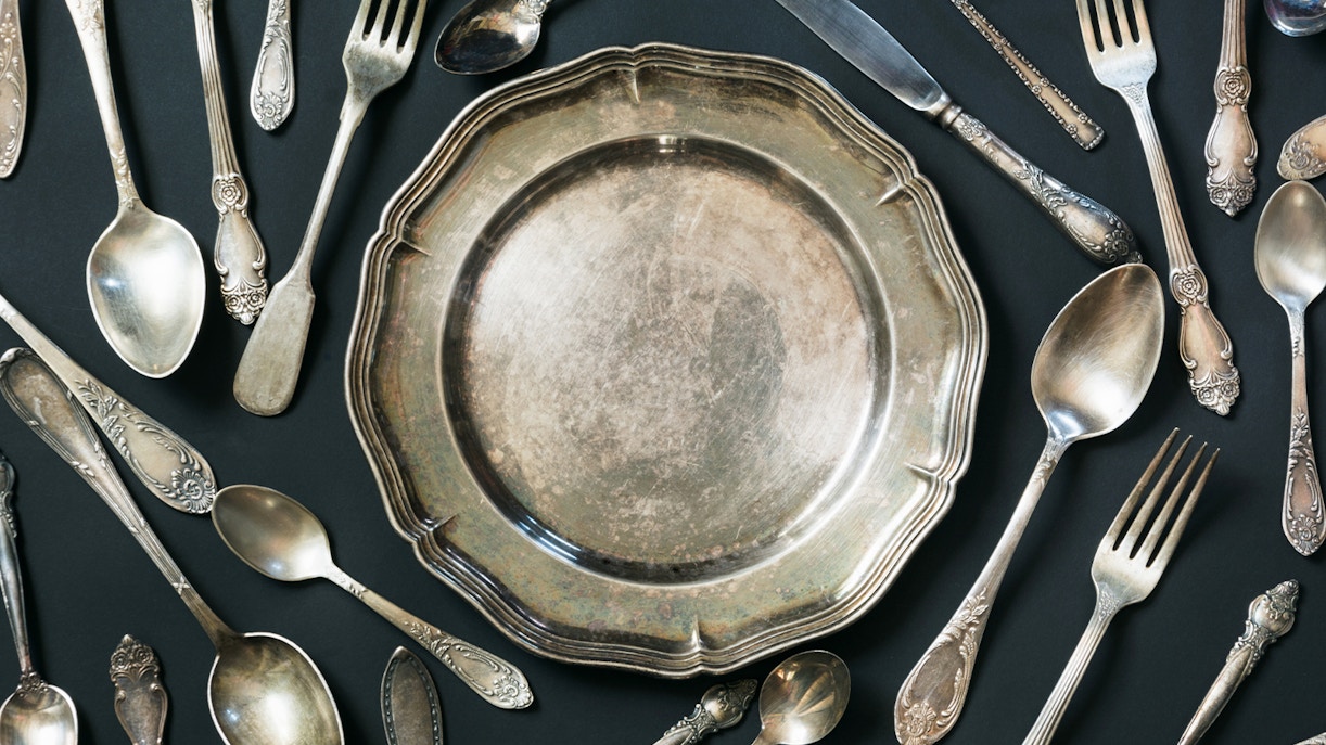 Elegant silverware set displayed on a white tablecloth in a fine dining setting.