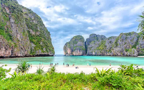 Phi Phi Islands beach with tourists, clear water, and limestone cliffs in Krabi.