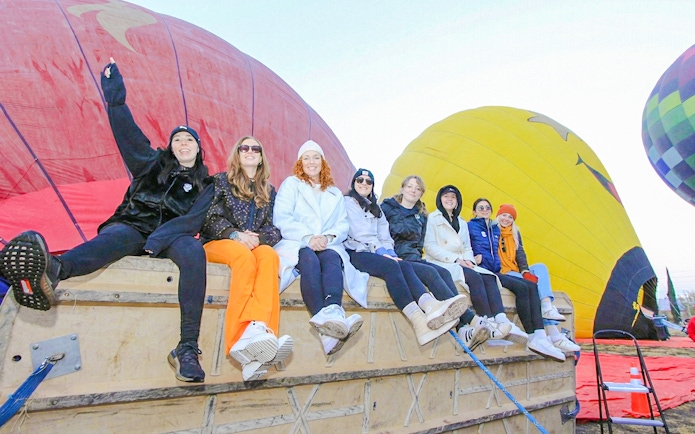 Group preparing for balloon flight at Teotihuacán with colorful balloons in the background.