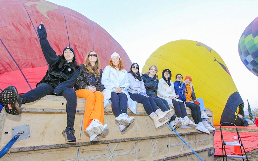 Group preparing for balloon flight at Teotihuacán with colorful balloons in the background.