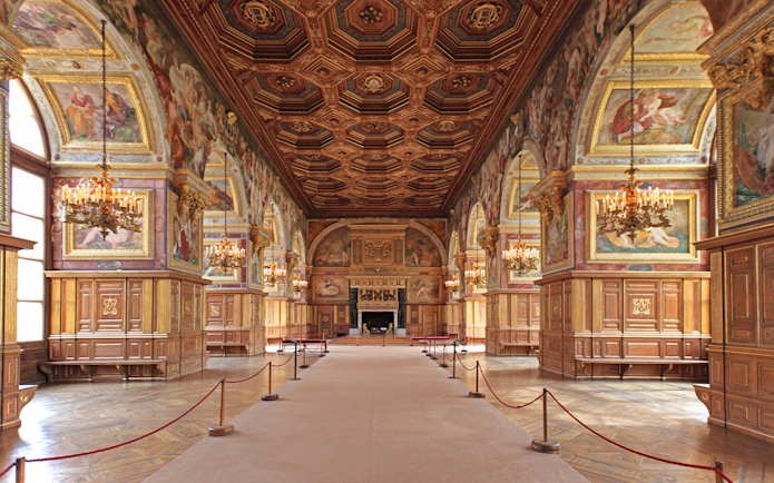 Château de Fontainebleau grand hall with ornate ceiling and chandeliers.