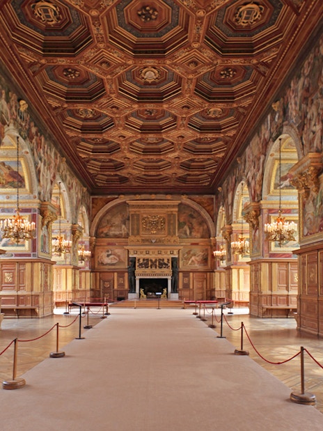 Château de Fontainebleau grand hall with ornate ceiling and chandeliers.