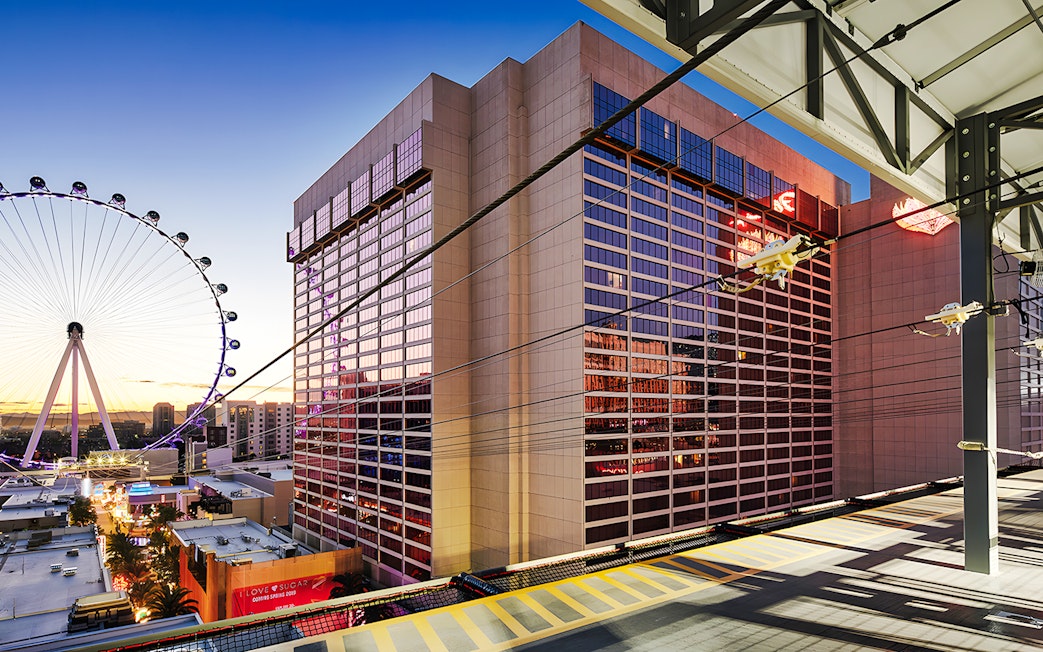 Fly LINQ Zipline view with High Roller Ferris wheel, Las Vegas skyline at sunset.