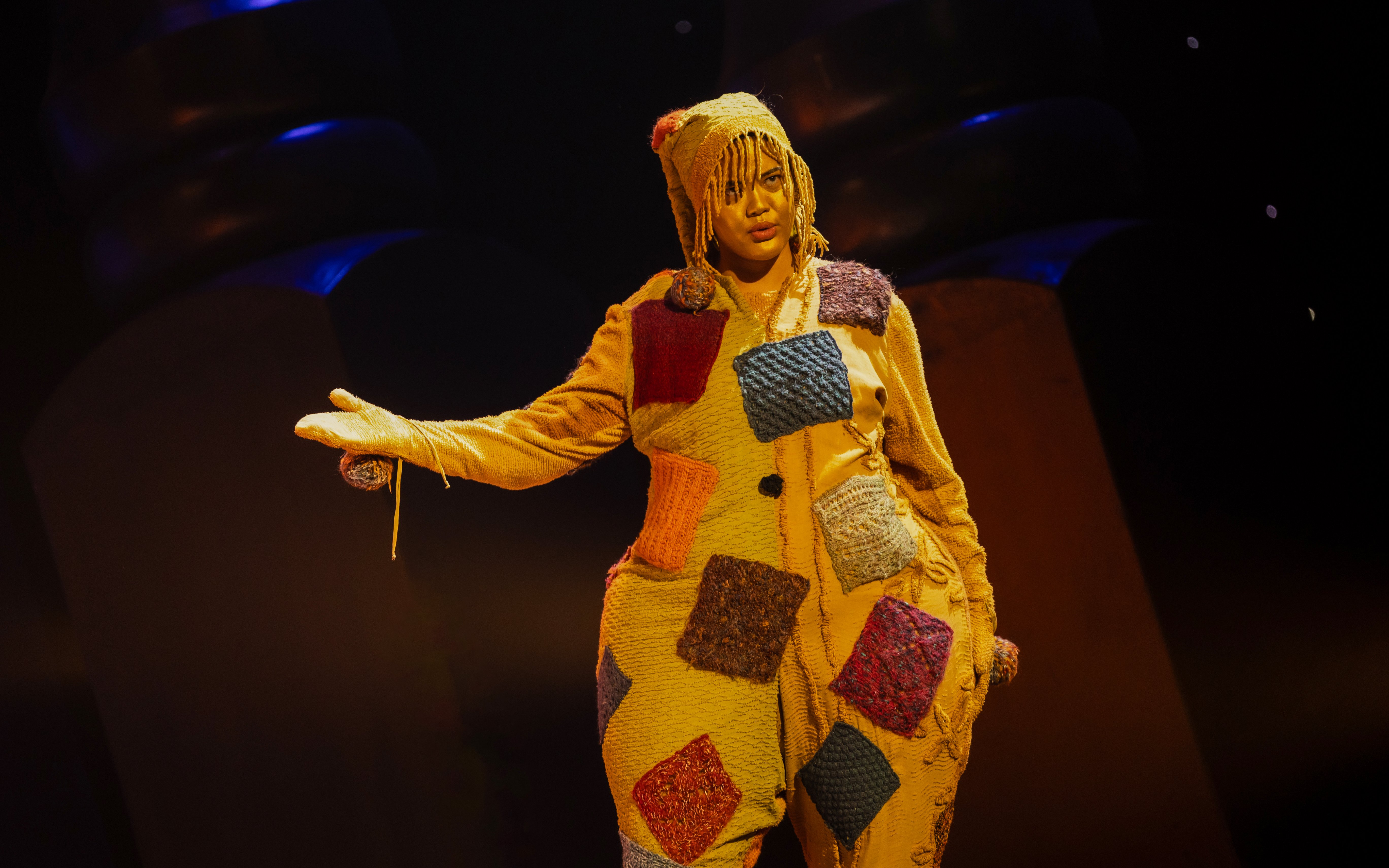Performer in colorful patchwork costume during Hansel and Gretel stage show.