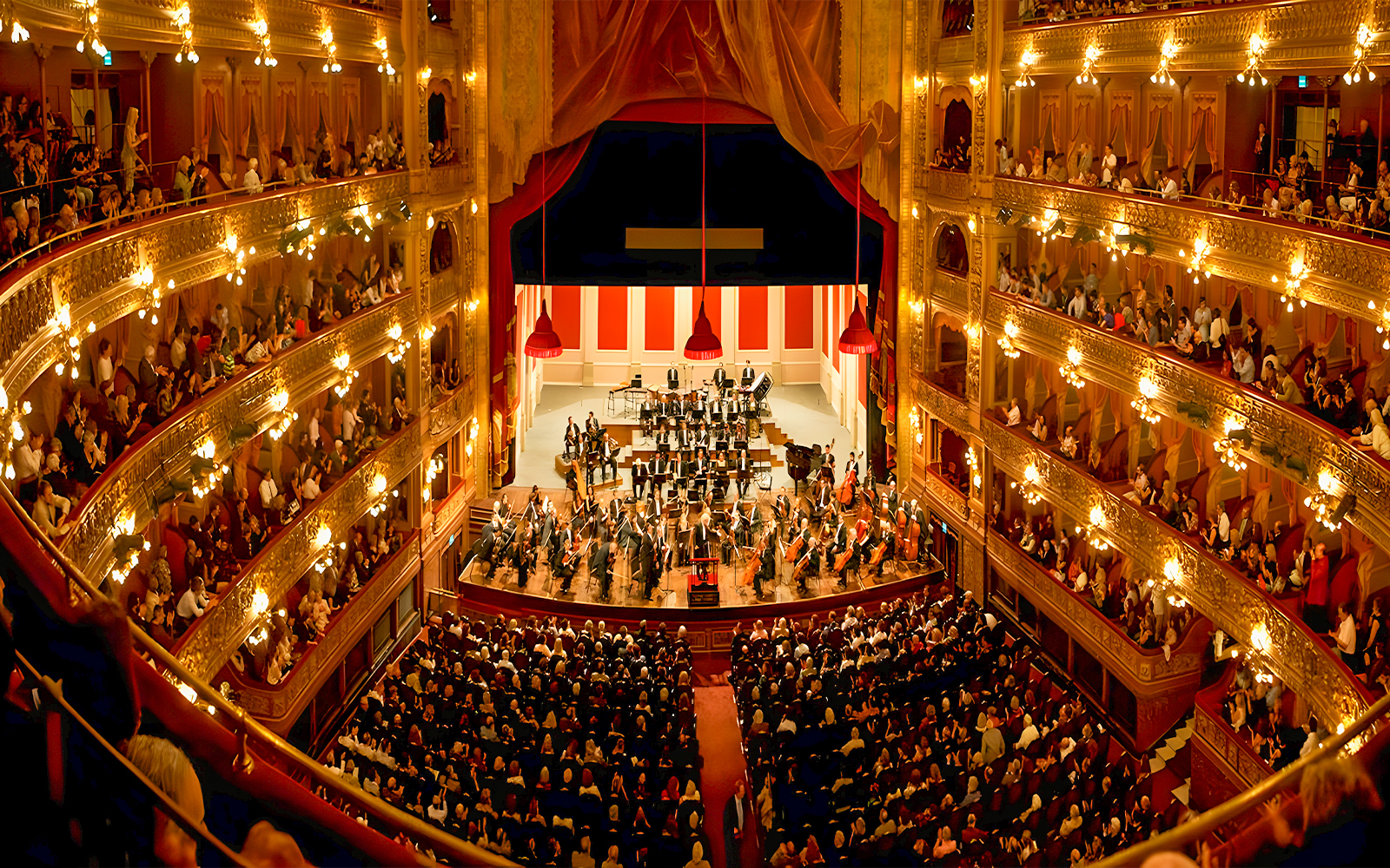 Teatro Colon interior with audience and orchestra on stage.