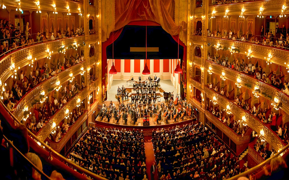 Teatro Colon interior with audience and orchestra on stage.