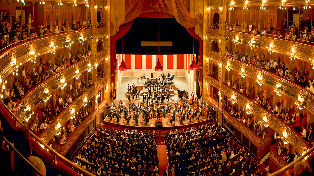 Teatro Colon interior with audience and orchestra on stage.