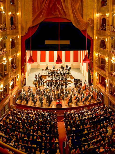 Teatro Colon interior with audience and orchestra on stage.