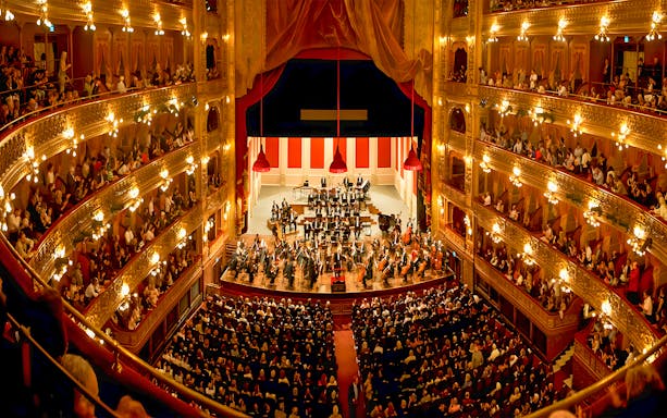 Teatro Colon interior with audience and orchestra on stage.
