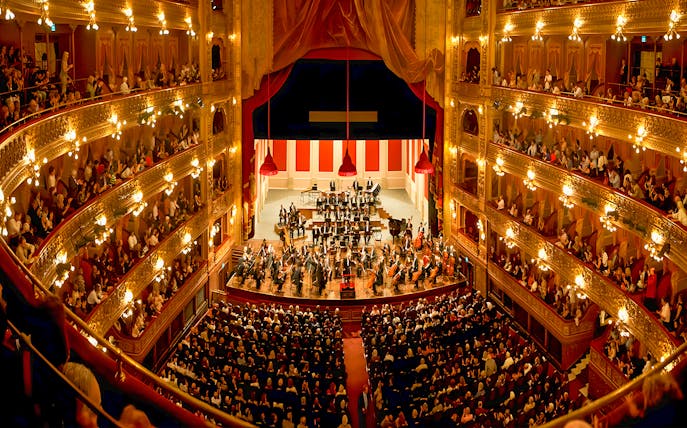 Teatro Colon interior with audience and orchestra on stage.