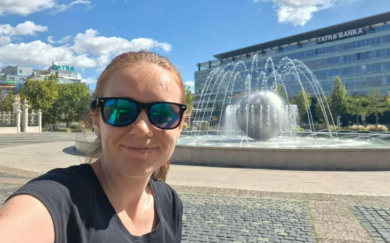 Fountain in Bratislava city center with a person in sunglasses in the foreground.