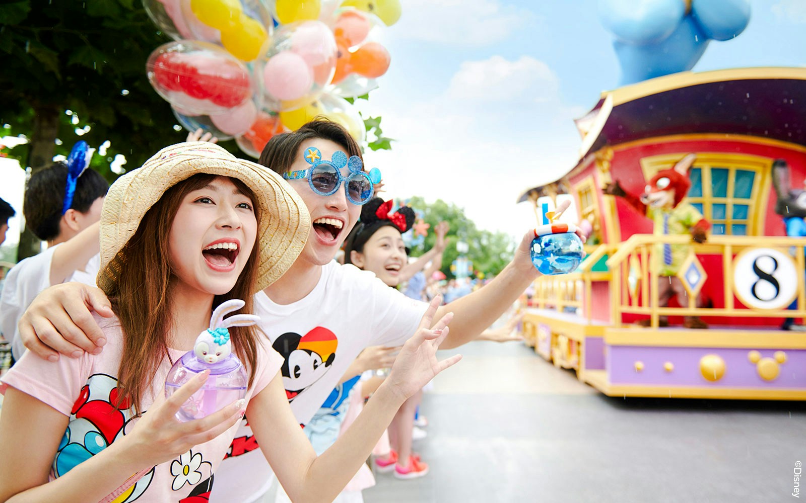 Visitors enjoying a colorful parade at Shanghai Disneyland with character floats.