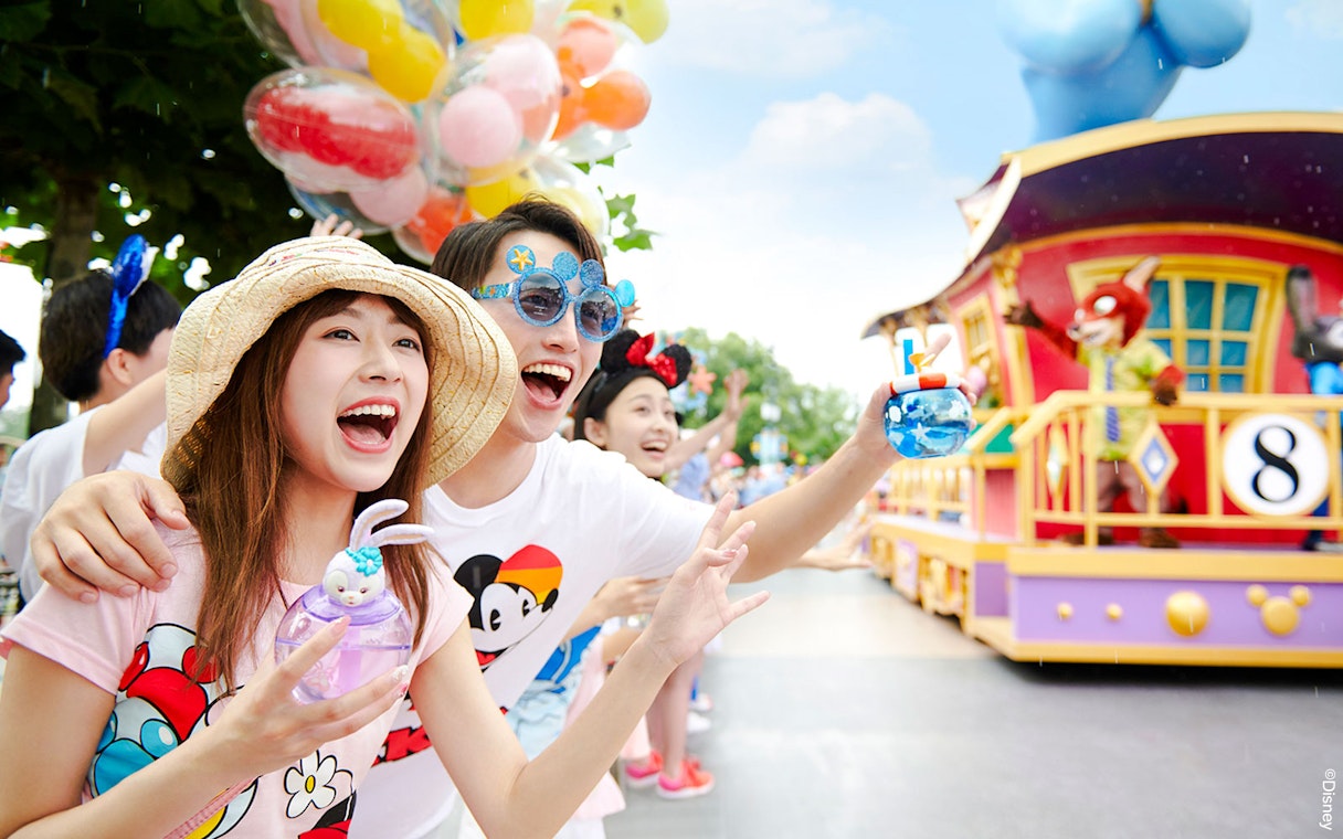 Visitors enjoying a colorful parade at Shanghai Disneyland with character floats.