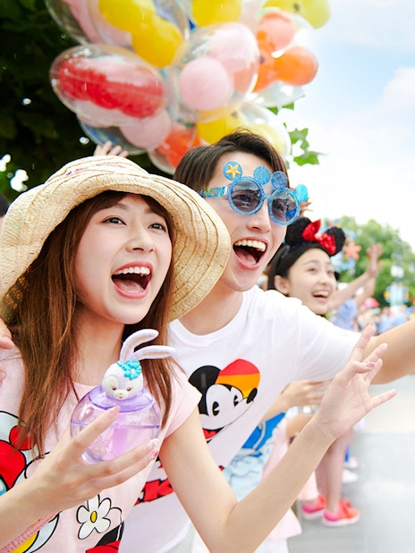 Visitors enjoying a colorful parade at Shanghai Disneyland with character floats.