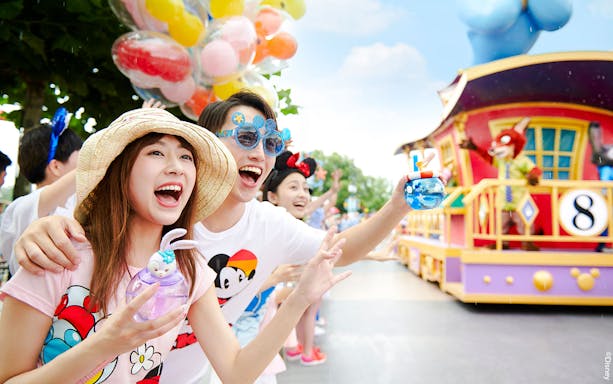Visitors enjoying a colorful parade at Shanghai Disneyland with character floats.
