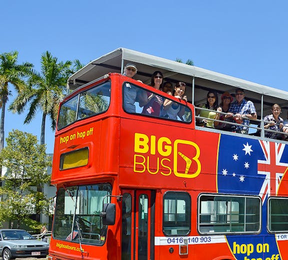 Red double-decker bus with tourists on a hop-on hop-off tour in Darwin, Australia.